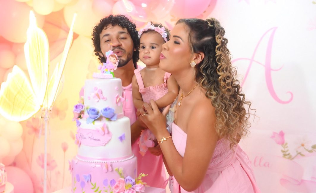Família soprando a velinha do bolo em festa de fadas e borboletas