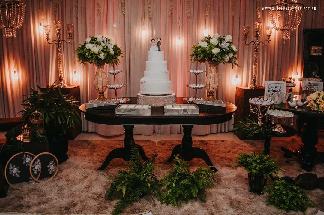 Mesa do bolo de casamento com flores brancas e velas