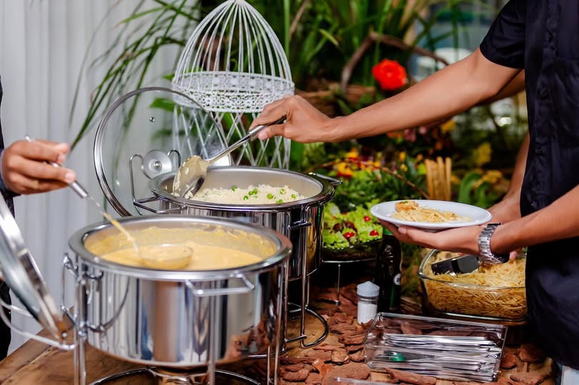 Buffet servindo arroz e massa em rechauds de inox no salão de festas